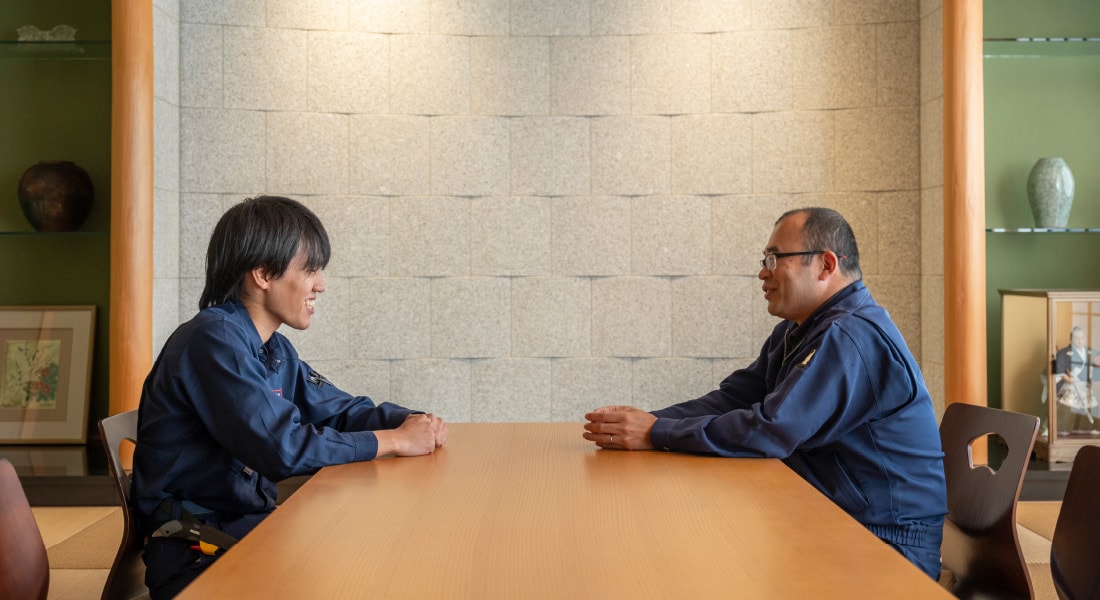 テーブルを挟んで向かい合い語り合う若手社員と先輩社員