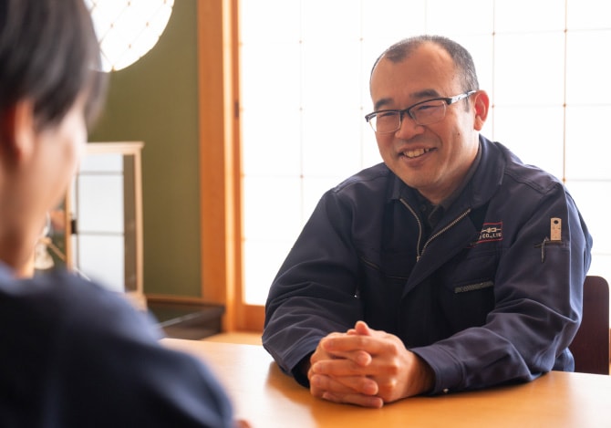 和室の机で手を組み、笑顔で語る百々