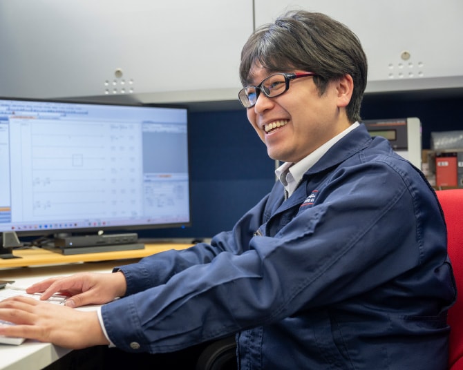 デスクでモニターに向かい笑顔を見せる社員